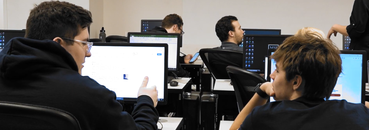 students sitting at desk on laptops