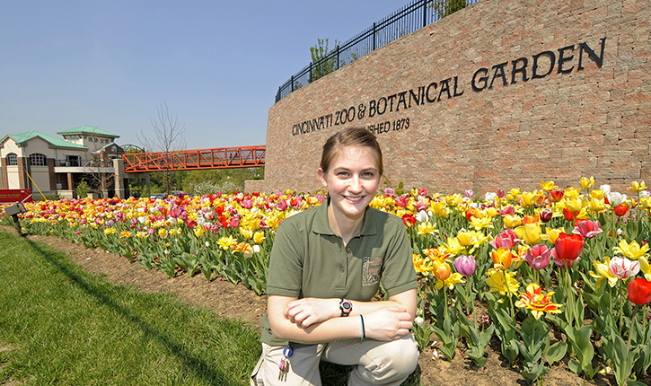 student sits in front of school sign