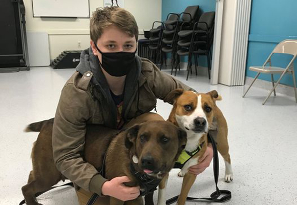 student sitting down with dogs