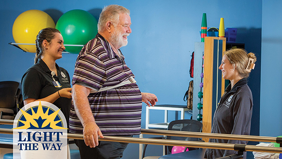 Two female MSJ physical therapists helping a man through walking bars