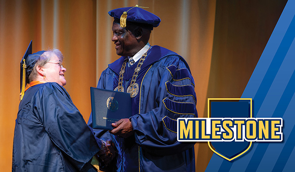 Mount St. Joseph University alumna susan niemoeller shaking dr. williams' hand in cap and gown at commencement.