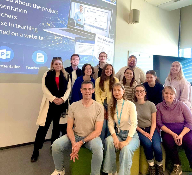 msj and finland students smiling by a powerpoint presentation
