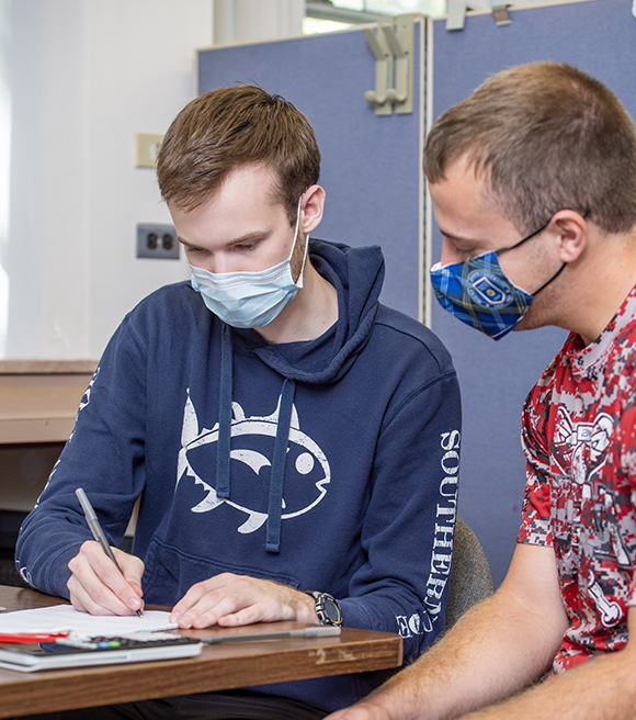 Two men study with COVID masks on