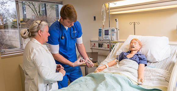 male nurse practicing administrating shots on simulation dummy