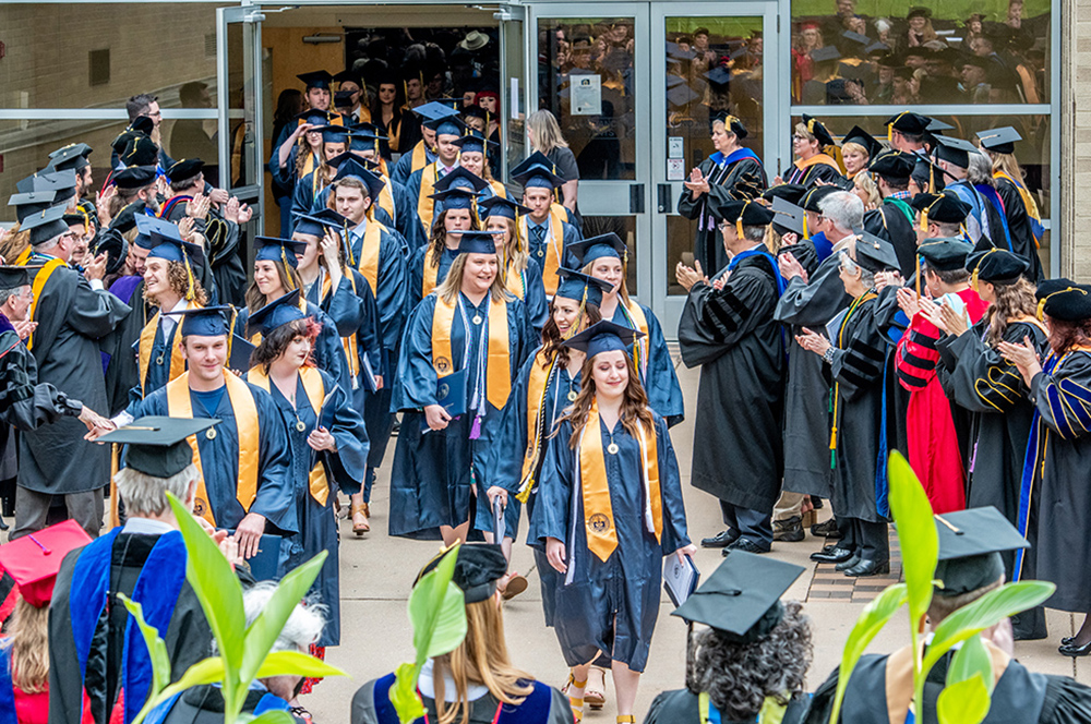 MSJ graduates leaving commencement ceremony awaiting faculty applause outside by Harrington.