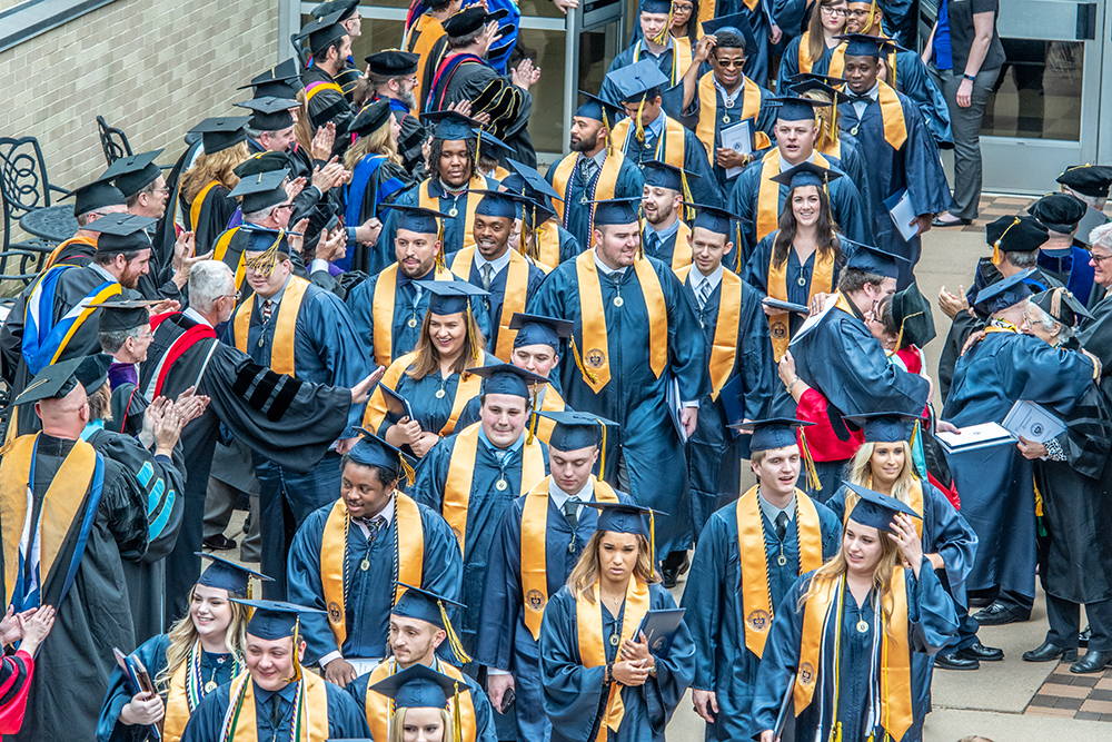 graduates walking out of commencement ceremony in gowns.