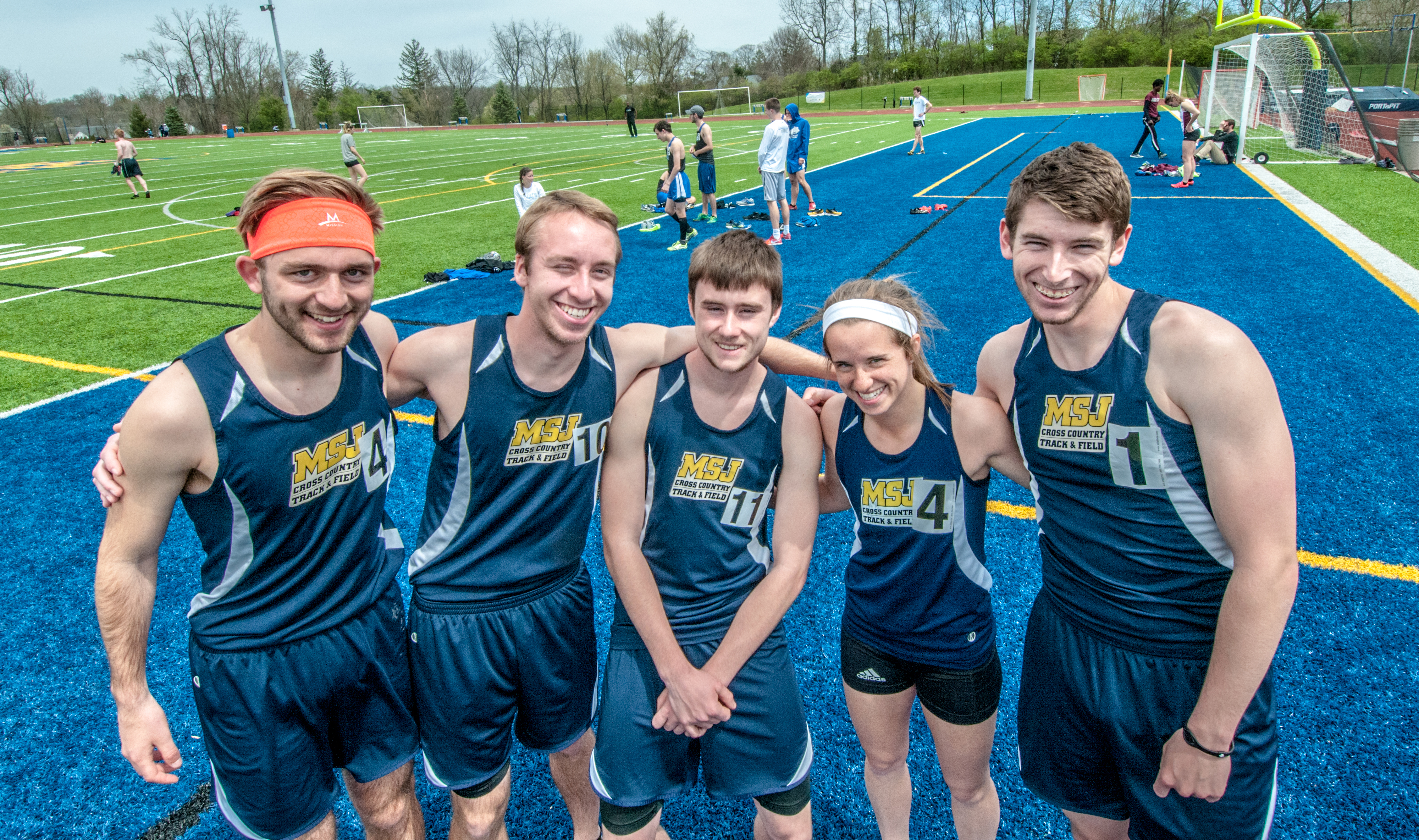 male and female athletes smiling in group photo on track