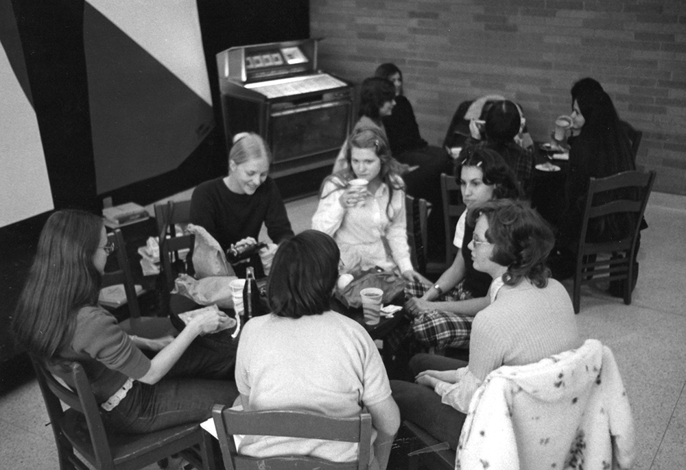 1964 alumni women sitting at table in historical photo.