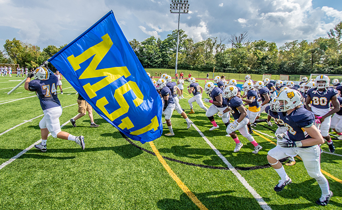 football players running on field with flag