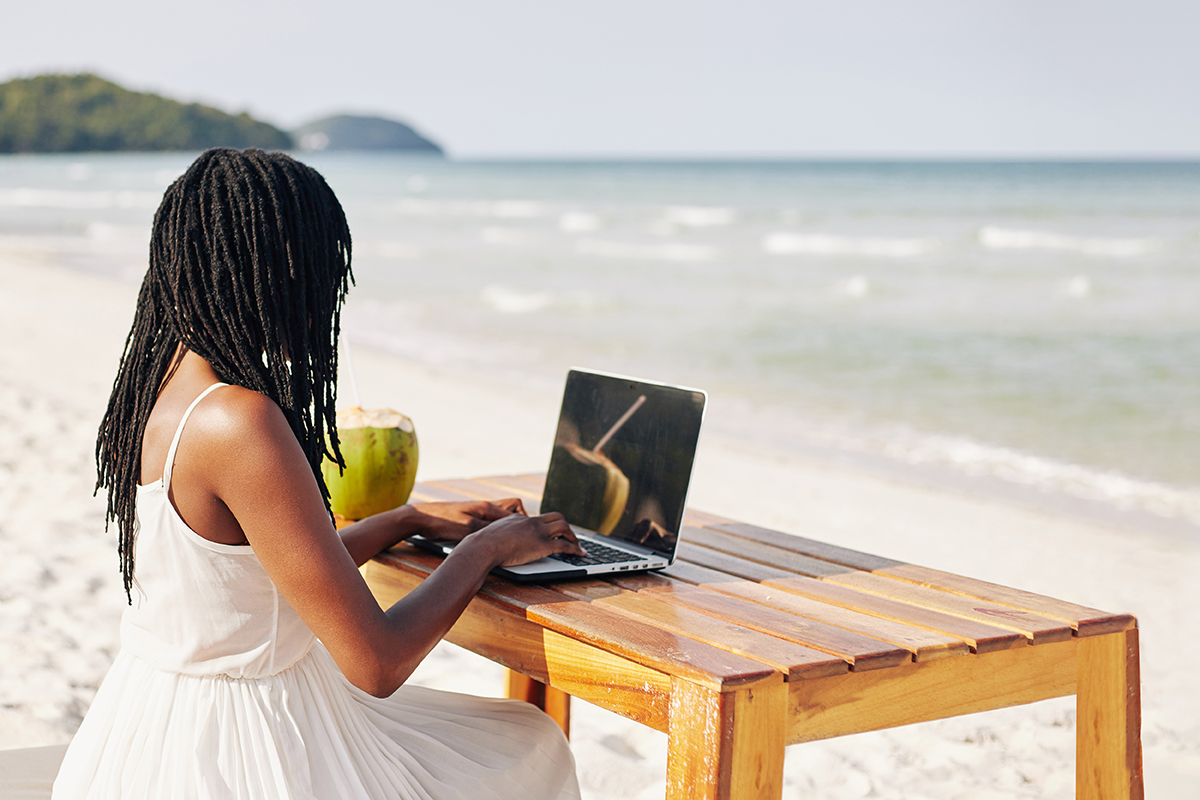 female student on laptop by the beach.