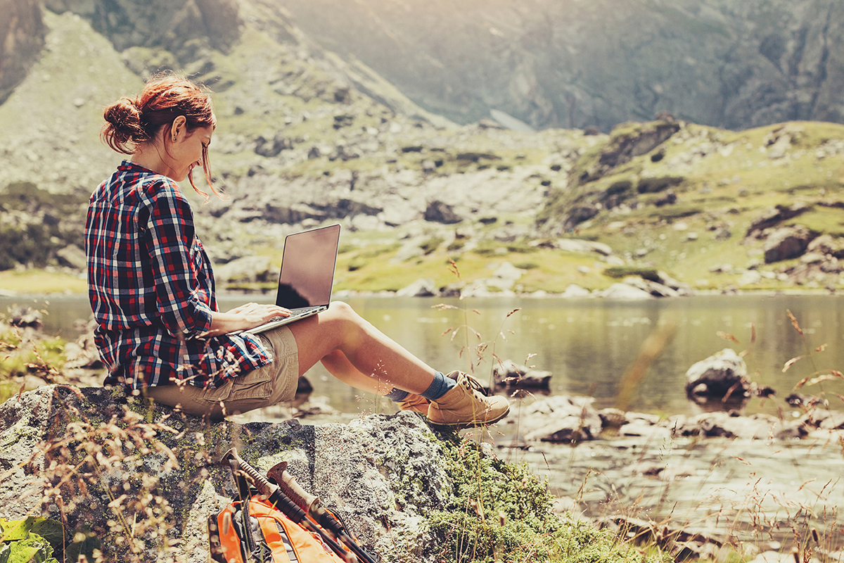 female student in hiking wear sitting on rocks by a lake.