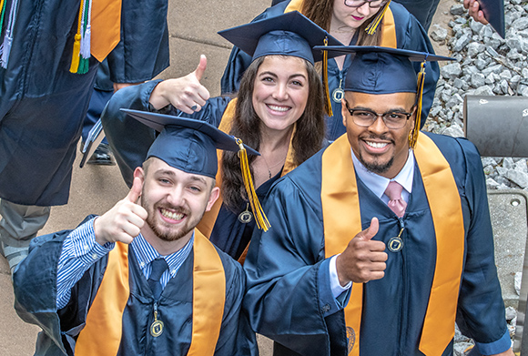 graduates giving a thumbs up to camera