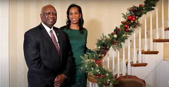 President and Mrs. Williams standing on festive staircase for a Holiday Message.