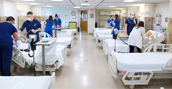 nursing students working on simulation dummies in lab room.