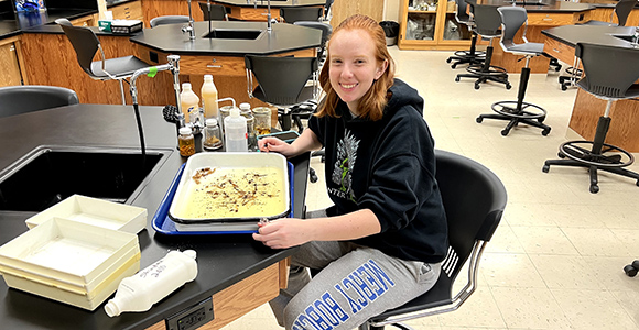 morgan cunningham, biology student sitting in classroom examining specimen.