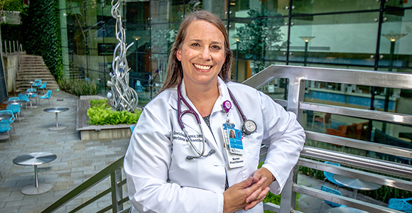 MSJ DNP graduate, gretchen rogers holding clipboard in front of Cincinnati Children's Hospital.