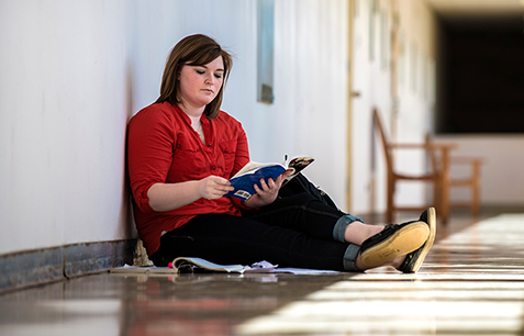 girl reading book in hallway