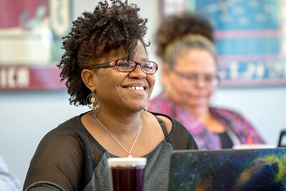 graduate student sitting at desk smiling